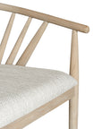 Lightwood spindle dining chair with a curved backrest and white upholstered seat, showcasing a modern yet timeless design. Crafted from solid wood, this chair brings a refined, natural aesthetic to any dining or living space