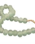 Decorative strand of recycled glass beads in a soft green hue, displayed on a minimalist black metal stand. A unique accent piece that adds texture and artisanal charm to any interior styling