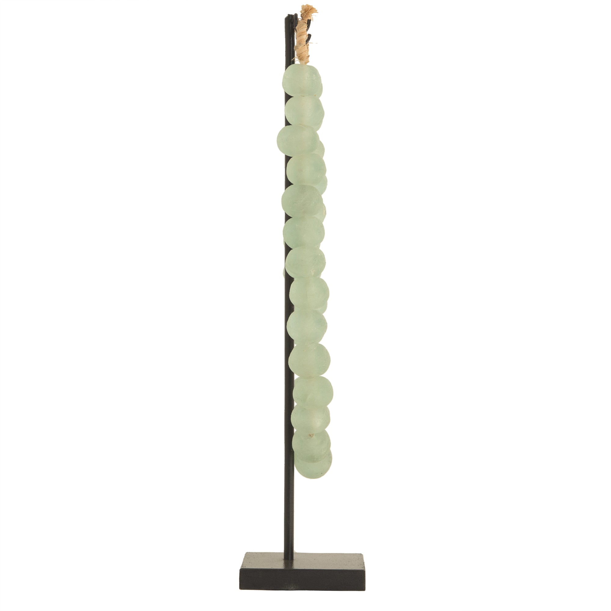 Decorative strand of recycled glass beads in a soft green hue, displayed on a minimalist black metal stand. A unique accent piece that adds texture and artisanal charm to any interior styling