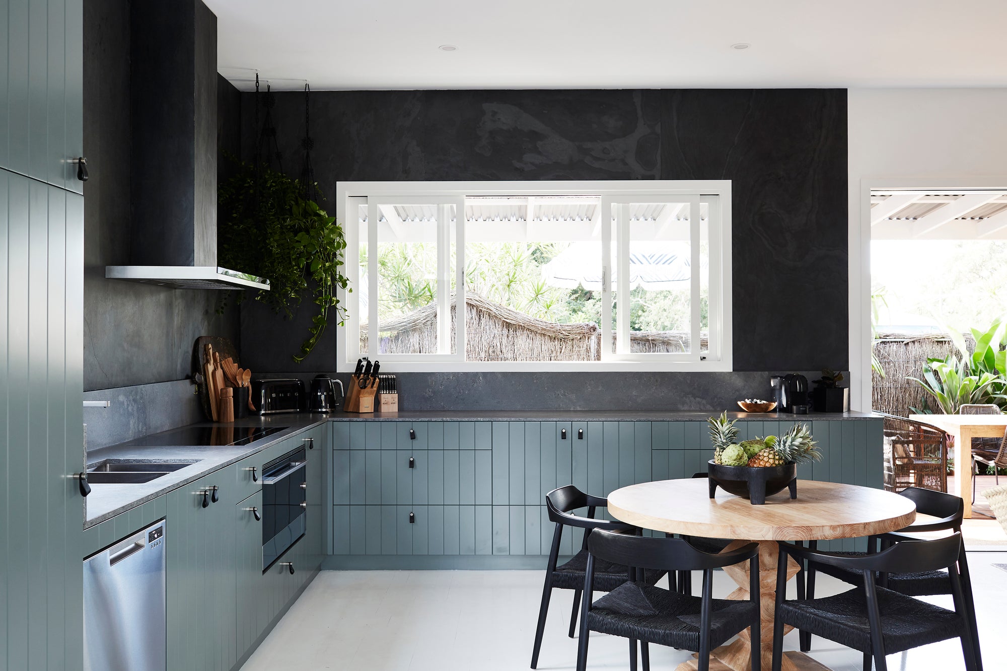 Contemporary kitchen with black dining chairs, a round wood table, and deep-toned cabinetry, creating a bold and stylish aesthetic