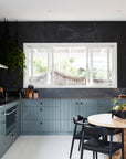 Contemporary kitchen with black dining chairs, a round wood table, and deep-toned cabinetry, creating a bold and stylish aesthetic