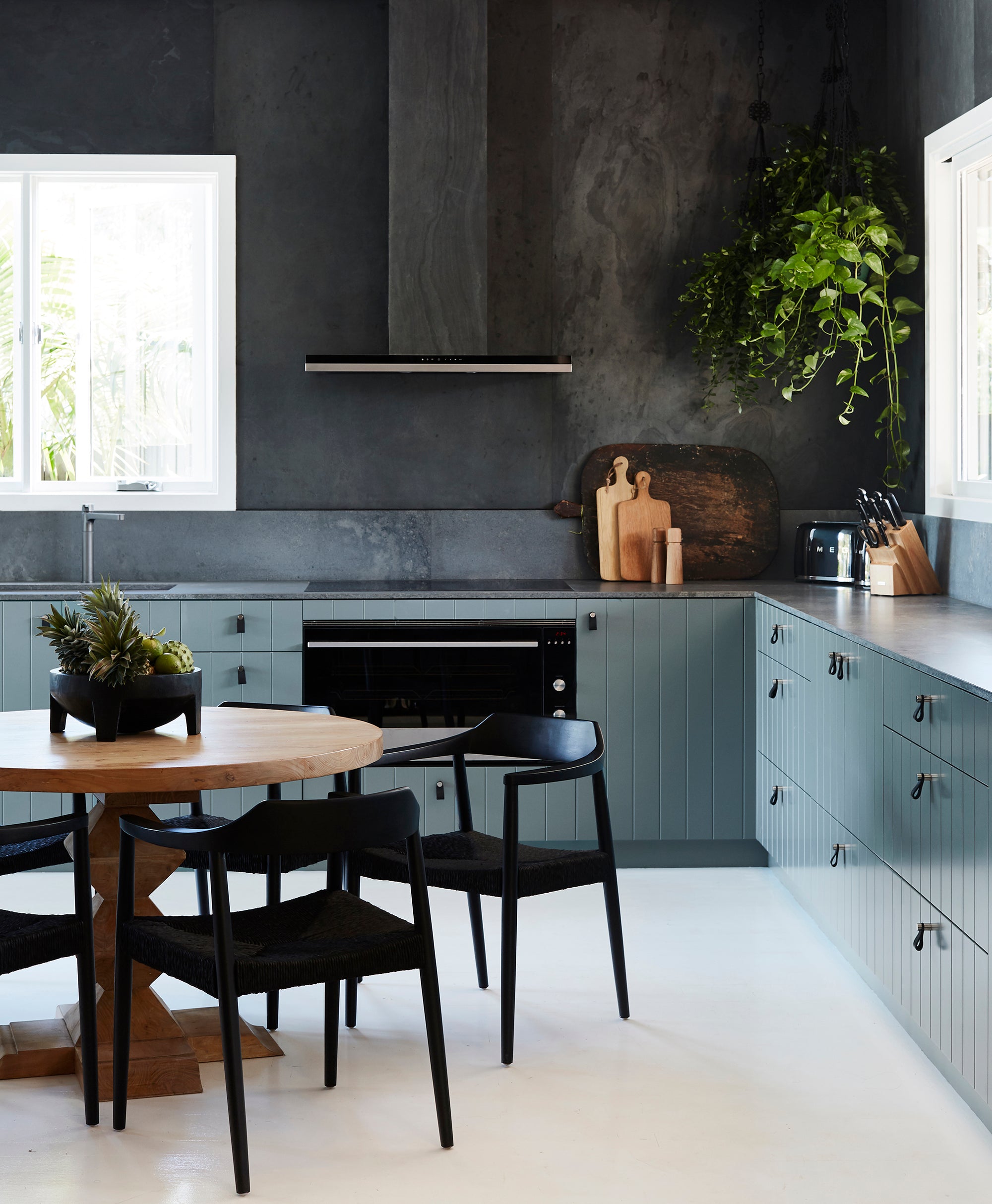 Contemporary kitchen with black dining chairs, a round wood table, and deep-toned cabinetry, creating a bold and stylish aesthetic