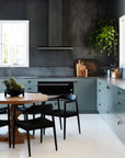 Contemporary kitchen with black dining chairs, a round wood table, and deep-toned cabinetry, creating a bold and stylish aesthetic