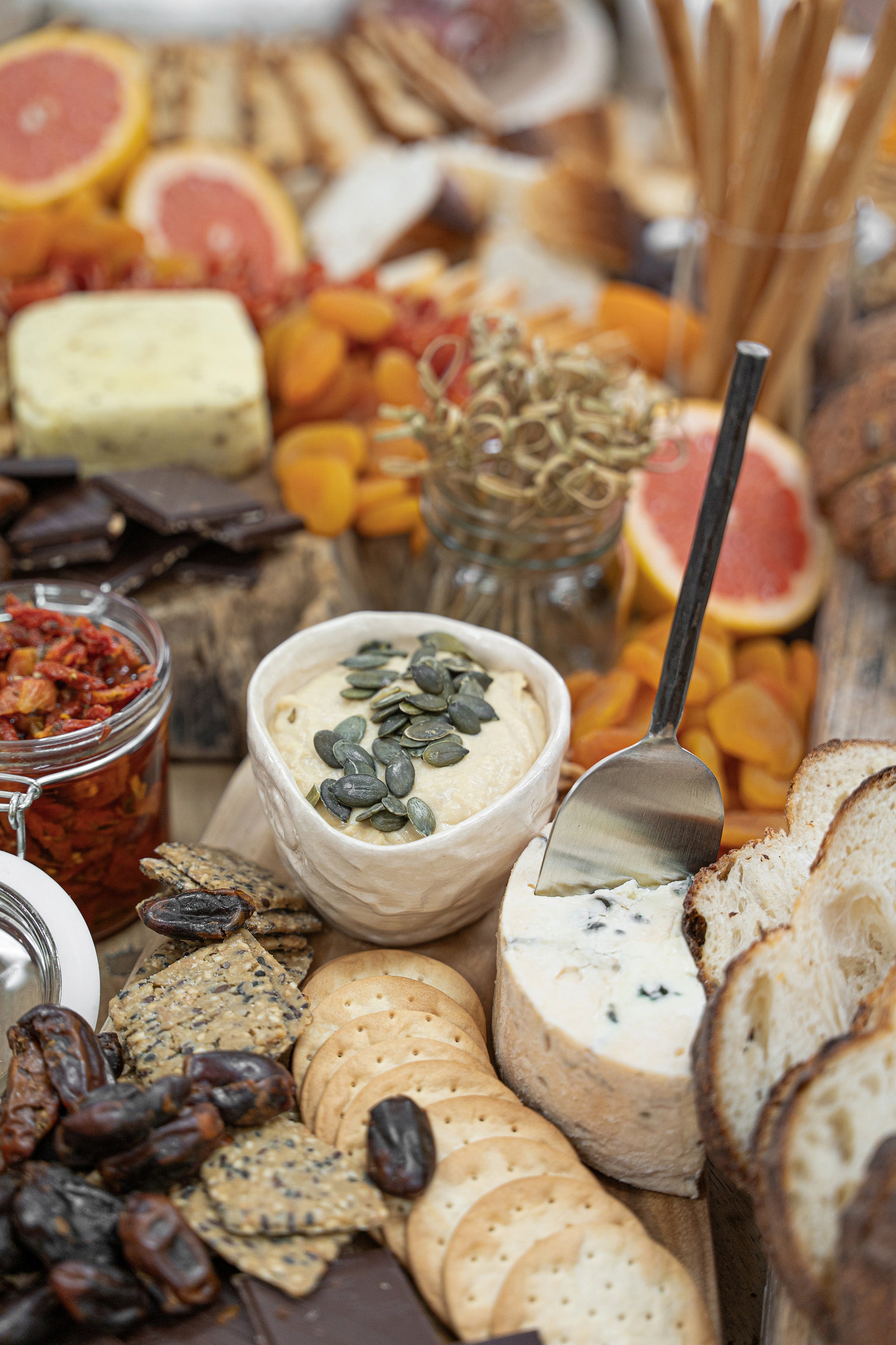 A beautifully styled grazing board featuring KULALA Living’s black cheese knife, artisanal cheeses, hummus topped with pumpkin seeds, dried fruits, crackers, and gourmet accompaniments. A sophisticated spread perfect for effortless entertaining