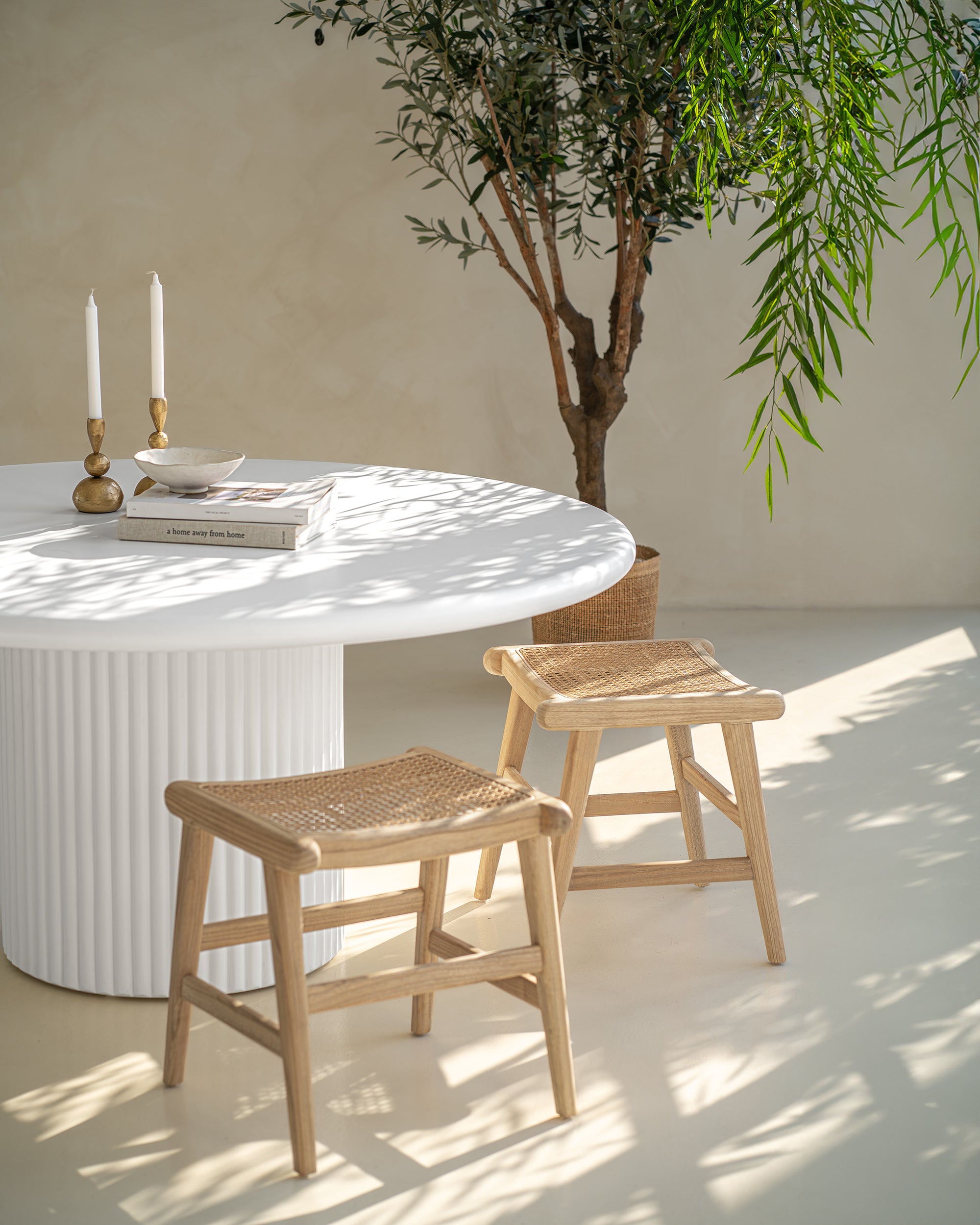 Coastal-inspired dining space featuring curved rattan dining chairs, paired with a white fluted dining table. Styled with candle holders, neutral-toned decor with organic ambiance