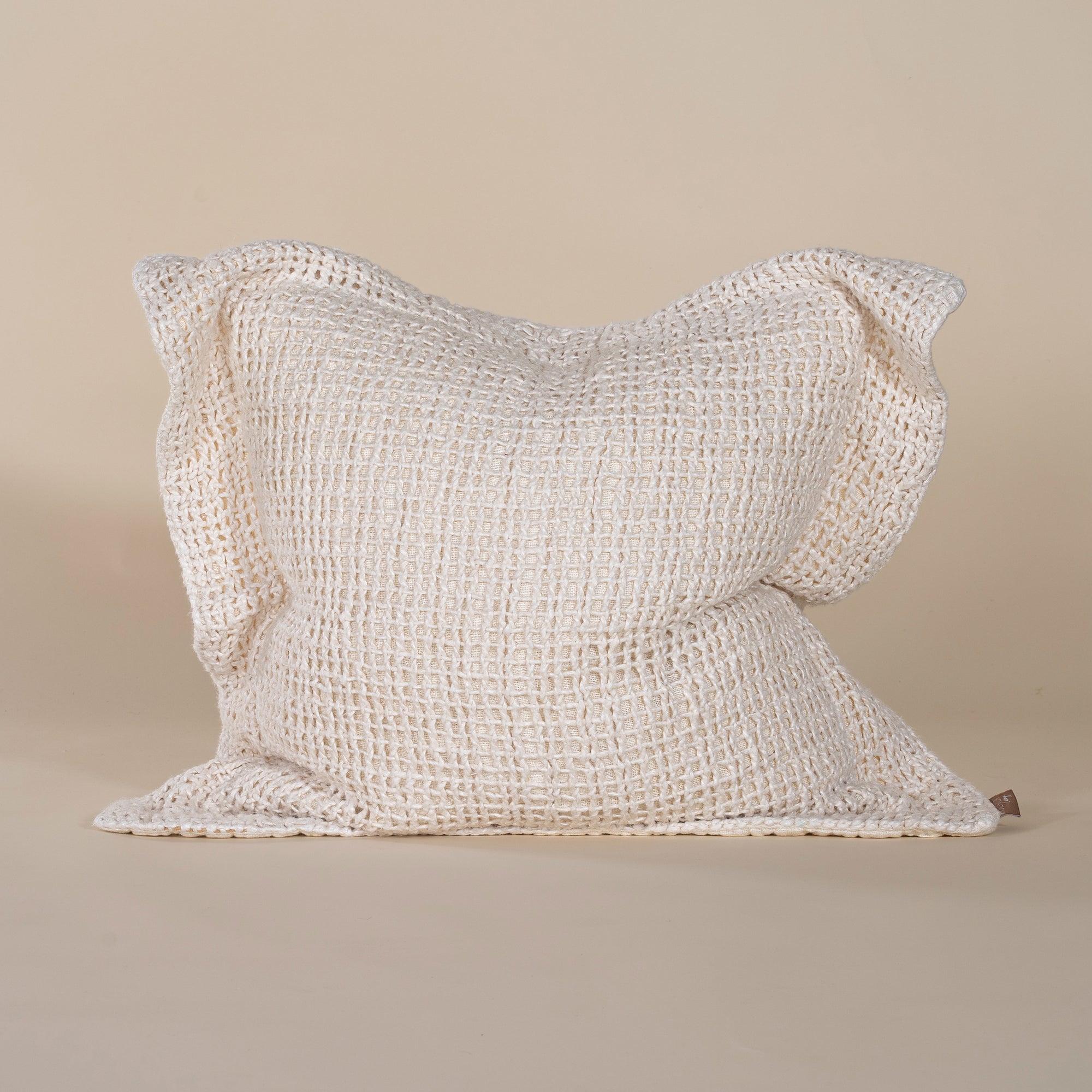 A handcrafted ivory cushion with an open-weave texture, made from natural fibres, adding warmth and artisanal charm to any living space