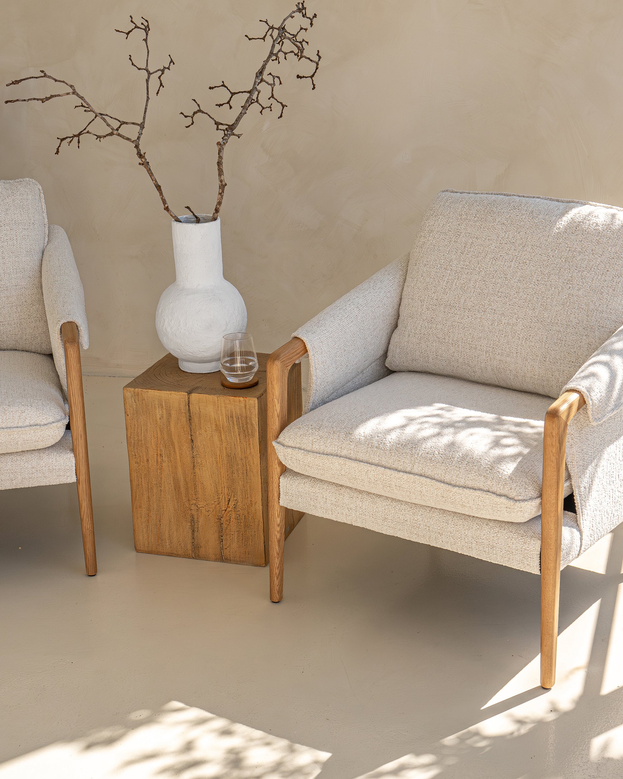 A beautifully styled pair of Hamptons-inspired armchairs from KULALA Living, featuring natural oak frames and soft linen upholstery. Set in a serene, light-filled space with a rustic wooden side table and a ceramic vase, exuding relaxed elegance