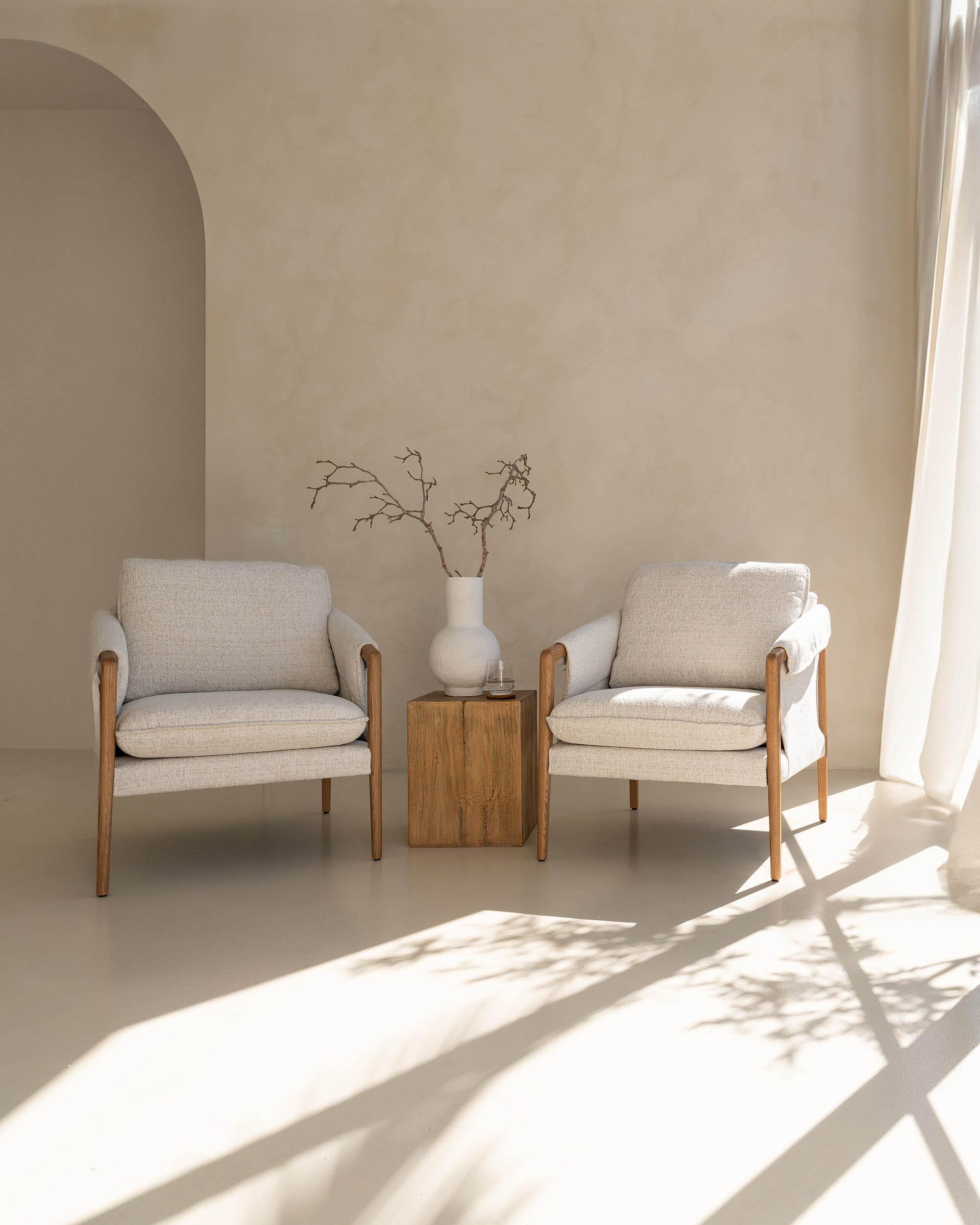 A beautifully styled pair of Hamptons-inspired armchairs from KULALA Living, featuring natural oak frames and soft linen upholstery. Set in a serene, light-filled space with a rustic wooden side table and a ceramic vase, exuding relaxed elegance