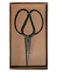 A pair of handcrafted black iron scissors with a vintage-inspired design, presented in a minimalist brown cardboard box