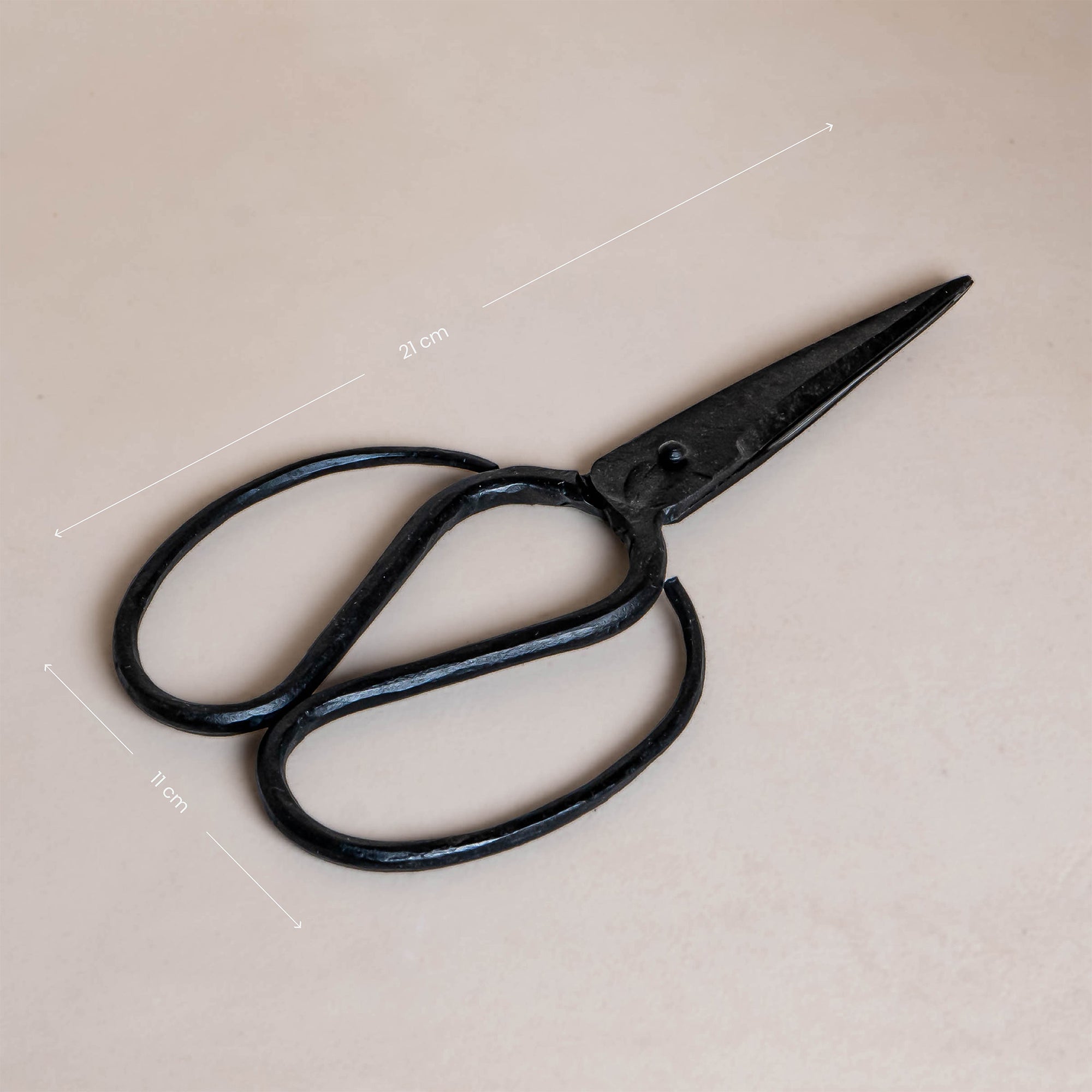 A pair of handcrafted black iron scissors with a vintage-inspired design, presented in a minimalist brown cardboard box