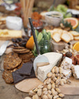 A beautifully styled grazing board featuring KULALA Living’s hand-forged cheese knife resting on a wedge of blue cheese, surrounded by gourmet crackers, dark chocolate, pistachios, and nougat. The perfect serving piece for effortless entertaining