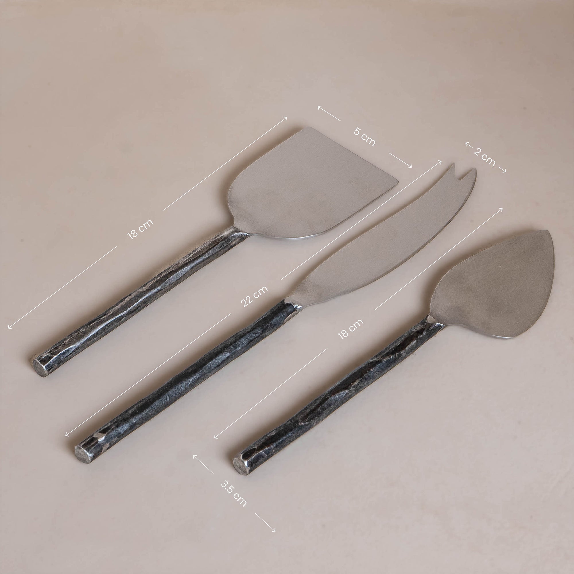 A set of three handcrafted stainless steel cheese knives with hand-forged handles, elegantly presented in a minimalist kraft gift box. Perfect for serving a variety of cheeses with style and sophistication