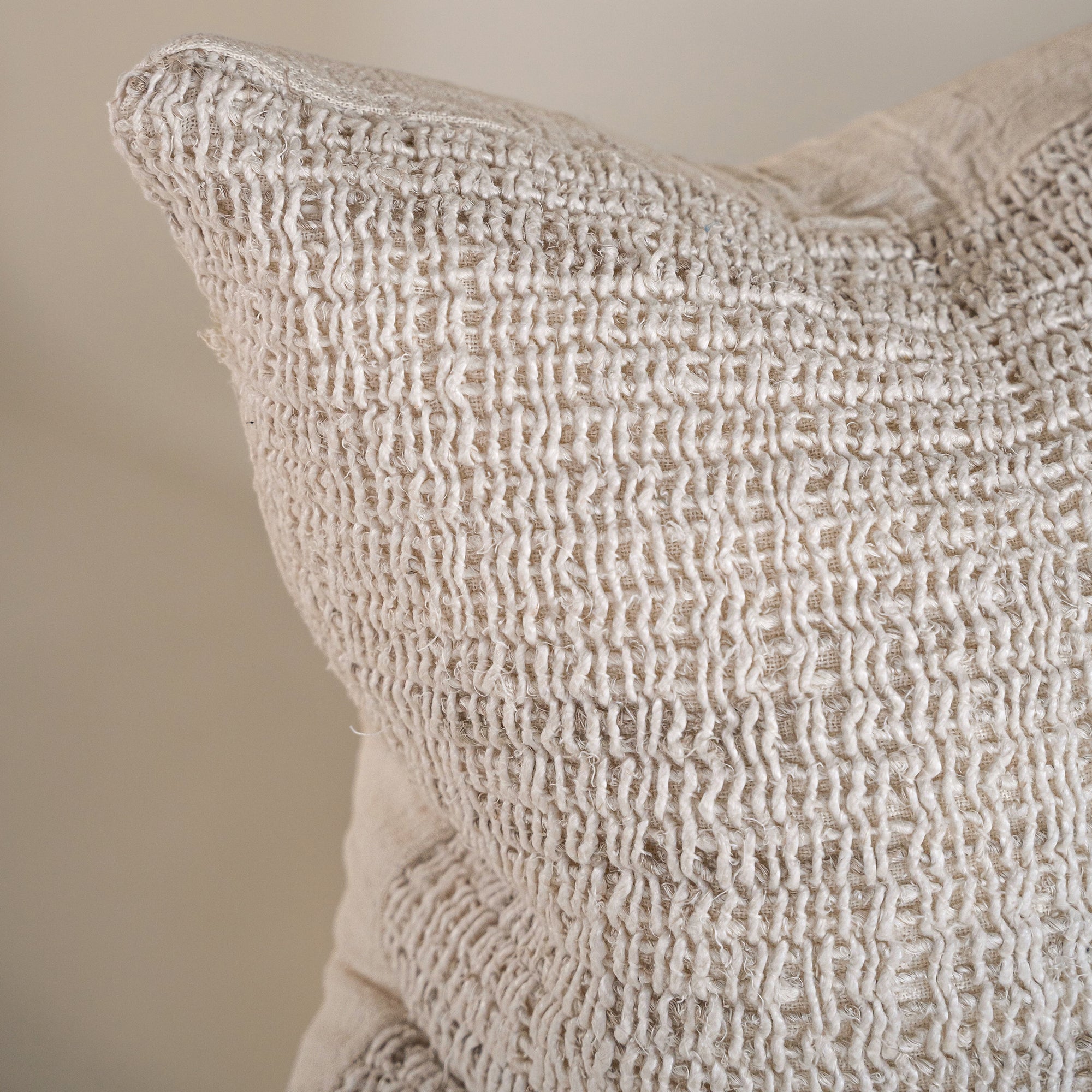 Detailed close-up of an off-white handwoven cushion, highlighting its intricate texture and natural woven fibres