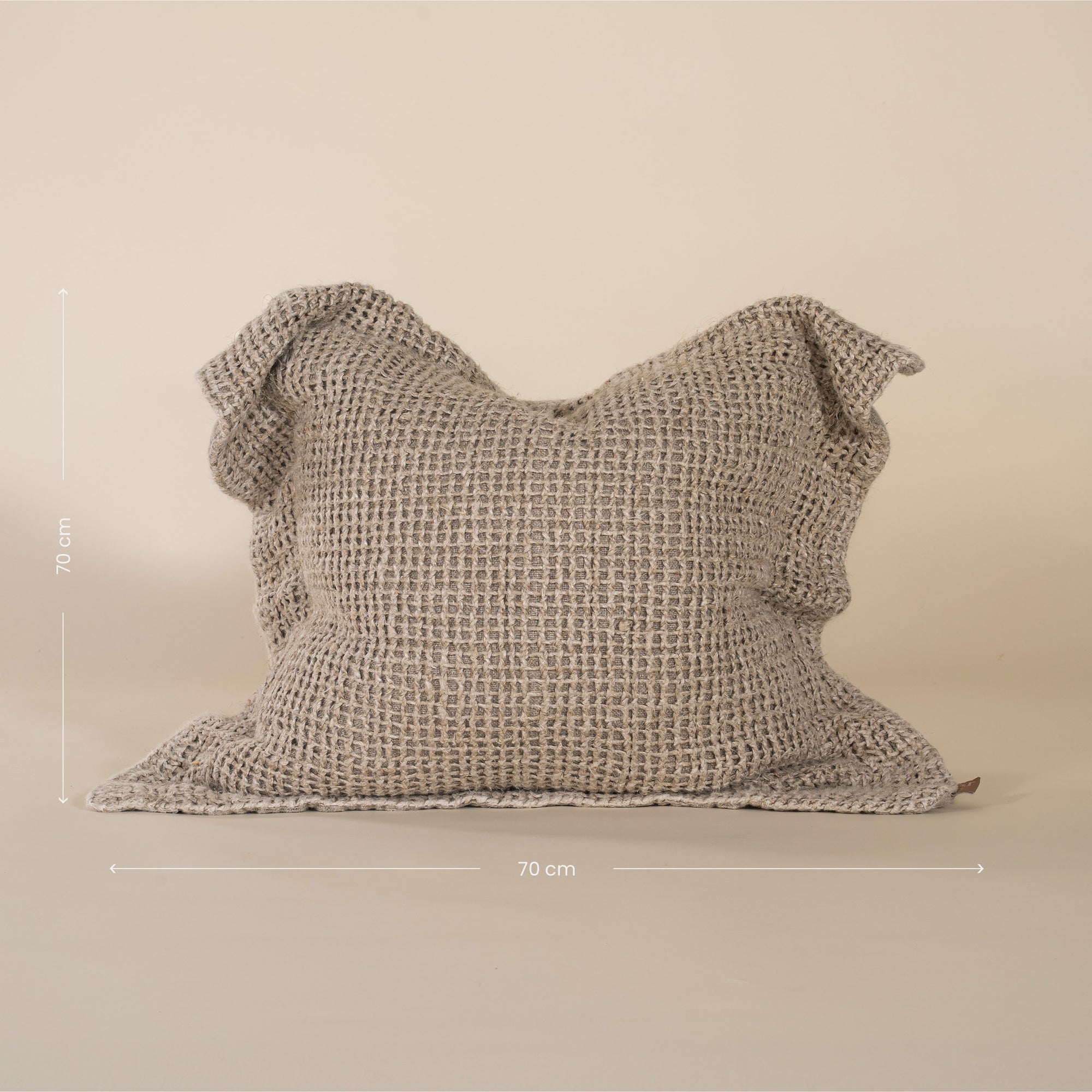 A handcrafted natural cushion with an open-weave texture, made from natural fibres, adding warmth and artisanal charm to any living space