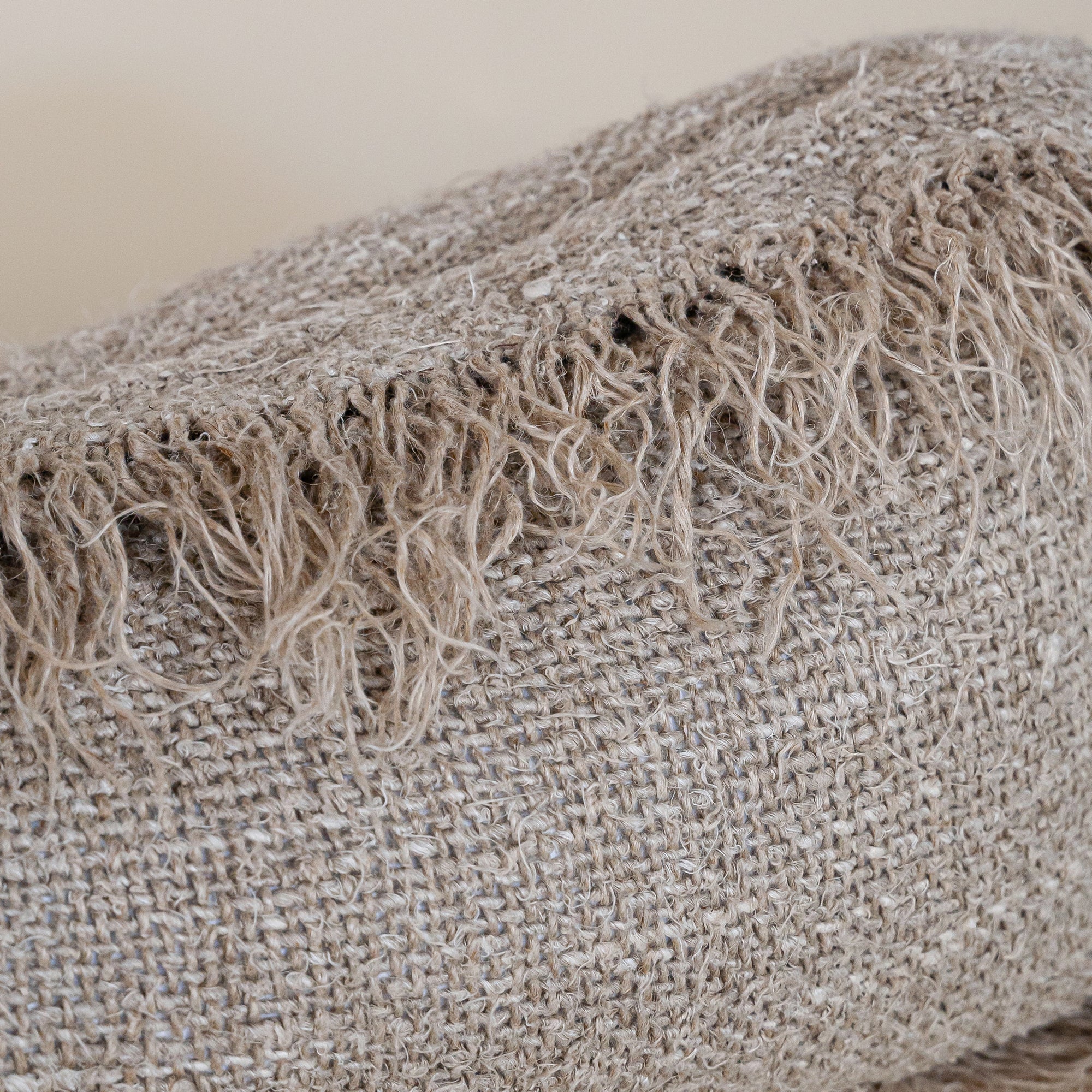 A handwoven cushion with natural fringe detailing, featuring an earthy, textured finish. This artisanal cushion adds warmth and organic style to any living space, complementing neutral and rustic interiors