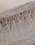 A handwoven cushion with natural fringe detailing, featuring an earthy, textured finish. This artisanal cushion adds warmth and organic style to any living space, complementing neutral and rustic interiors