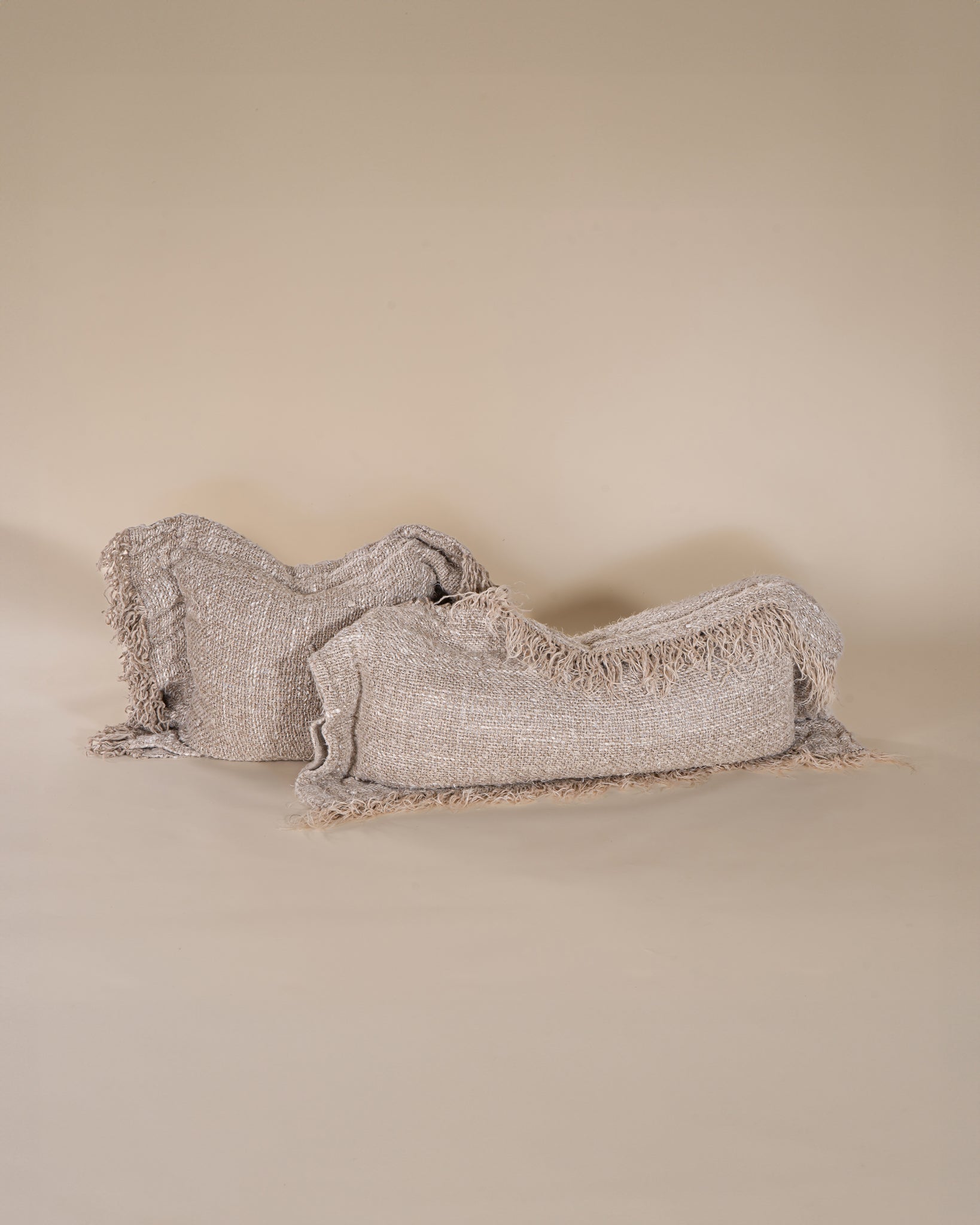 A handwoven cushion with natural fringe detailing, featuring an earthy, textured finish. This artisanal cushion adds warmth and organic style to any living space, complementing neutral and rustic interiors