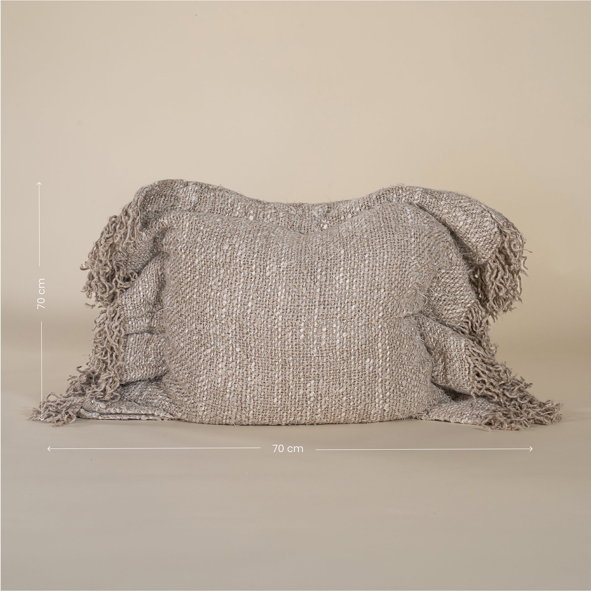 A handwoven cushion with natural fringe detailing, featuring an earthy, textured finish. This artisanal cushion adds warmth and organic style to any living space, complementing neutral and rustic interiors