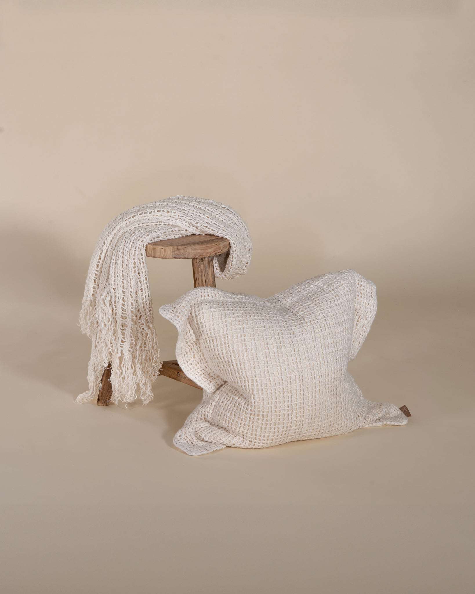 A handcrafted ivory cushion with an open-weave texture, made from natural fibres, adding warmth and artisanal charm to any living space.