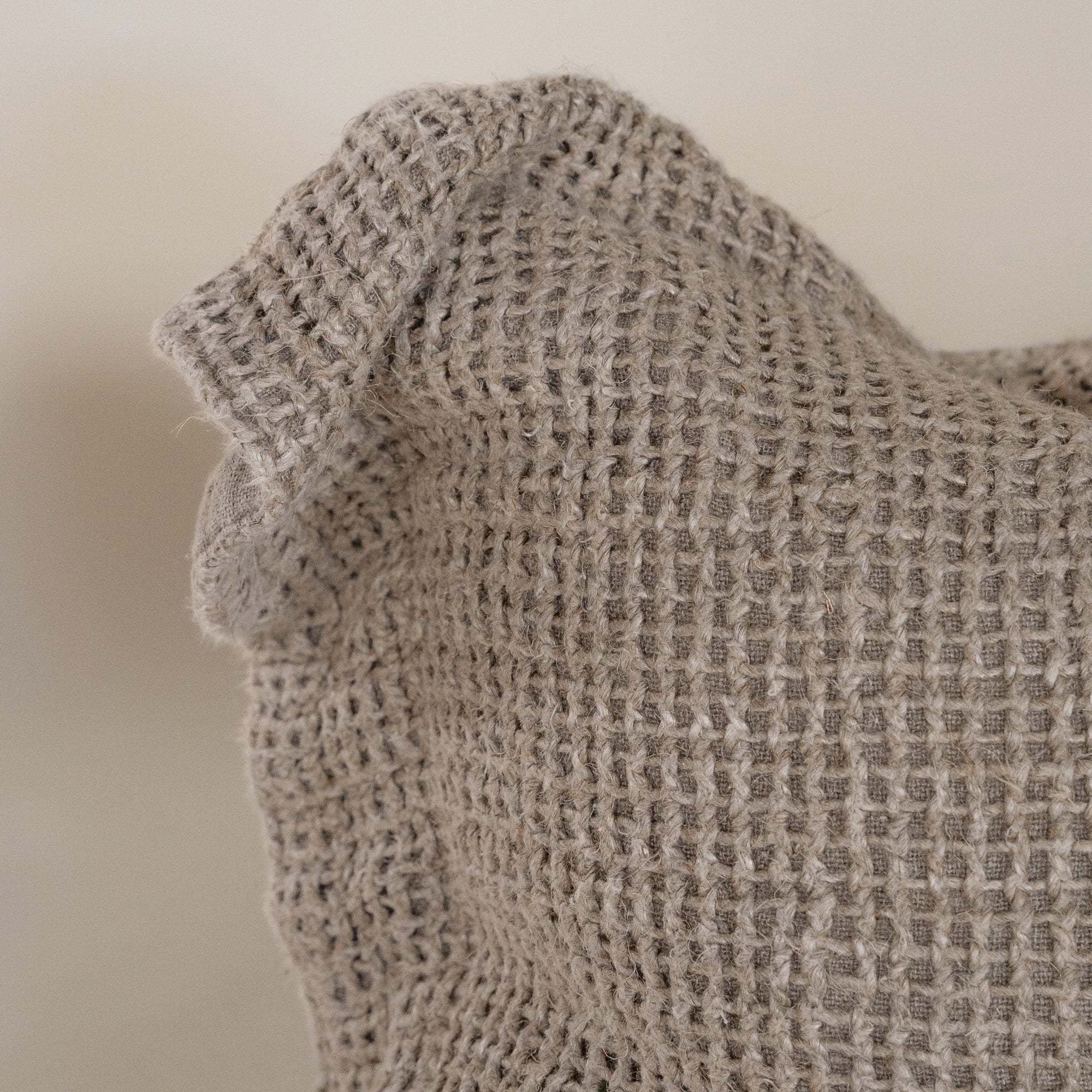 A handcrafted natural cushion with an open-weave texture, made from natural fibres, adding warmth and artisanal charm to any living space.