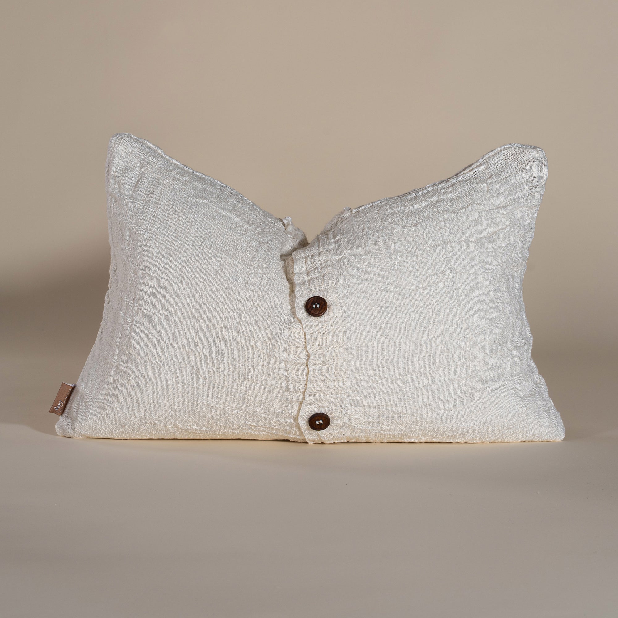 Handwoven linen cushion in a soft cream shade, featuring a button closure for a timeless and artisanal touch