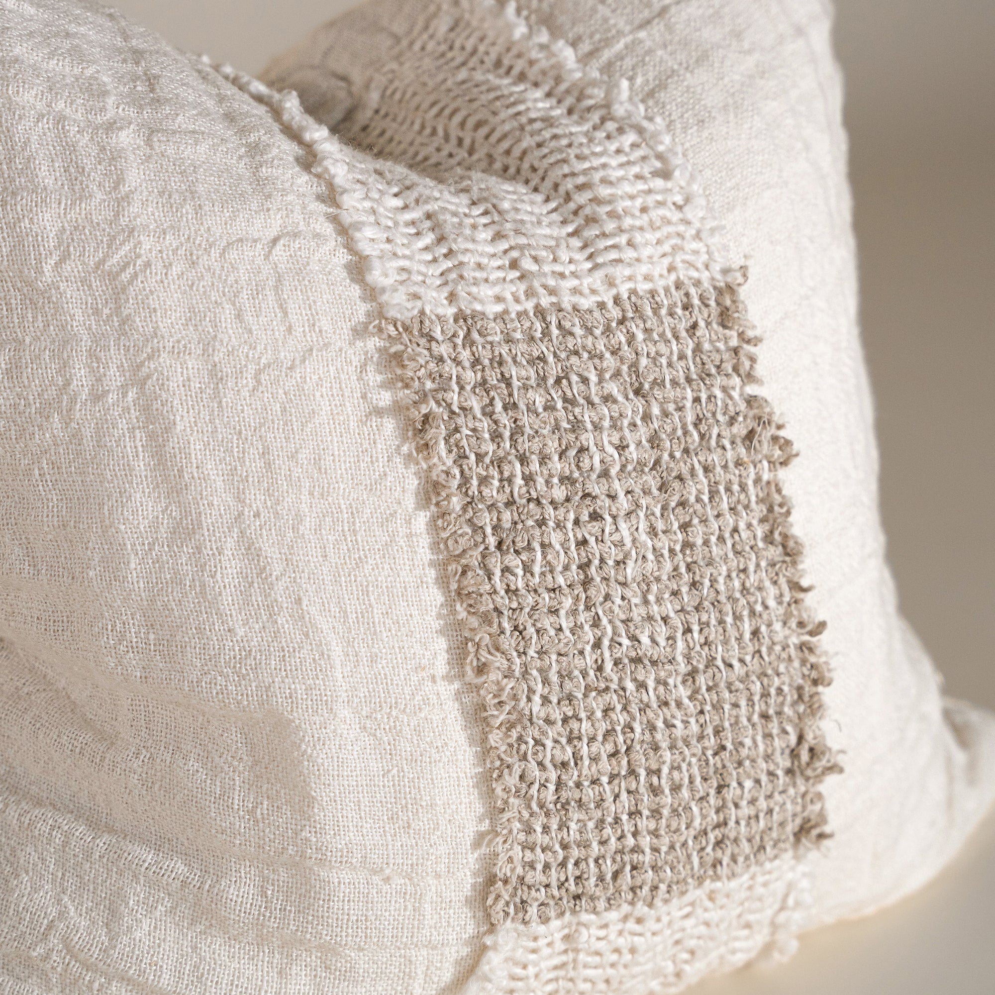 Handcrafted linen cushion in a soft cream hue, featuring a textured woven centre panel for a rustic yet refined aesthetic