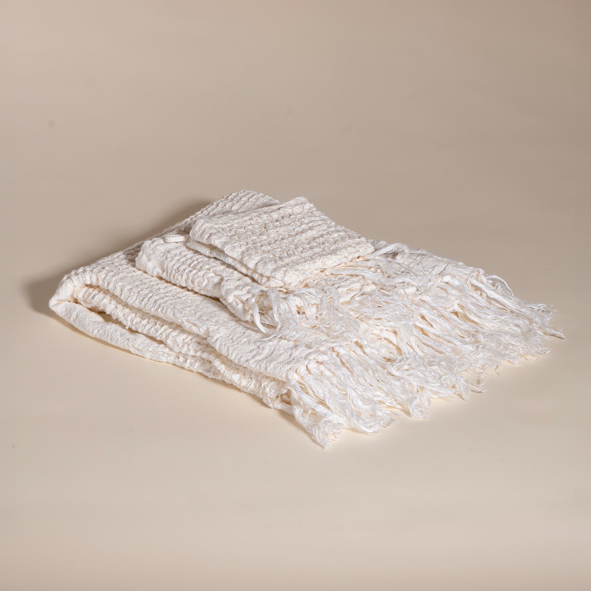 An elegant off-white handwoven linen throw from KULALA Living, featuring a soft texture and delicate fringed edges. A perfect layering piece for a relaxed, stylish home