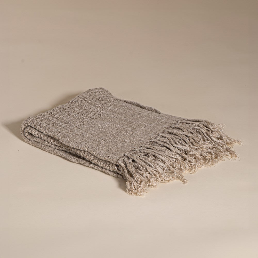 A beautifully handwoven linen throw from KULALA Living, featuring a soft texture and elegant fringed edges. Perfect for layering warmth and style in any space