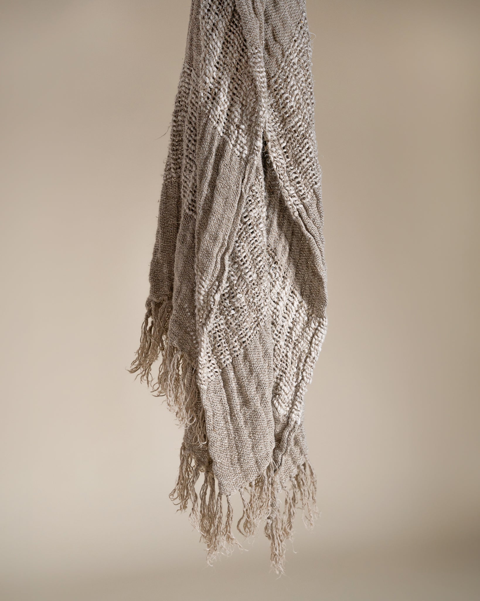 Handwoven natural throw with intricate texture and fringed edges, crafted in earthy tones to add warmth and softness to any space