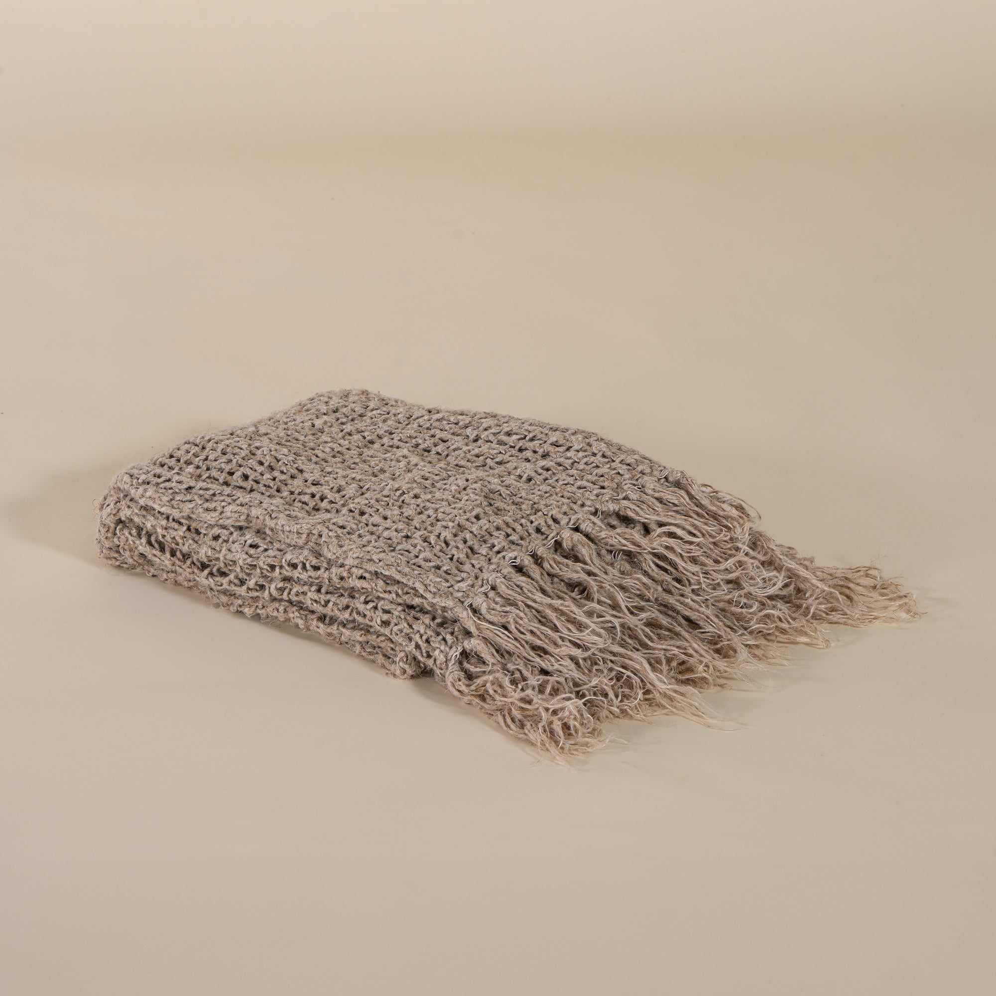 A soft, handwoven natural throw blanket with delicate fringe detailing, perfect for layering on a sofa or bed. Designed for warmth and effortless style.