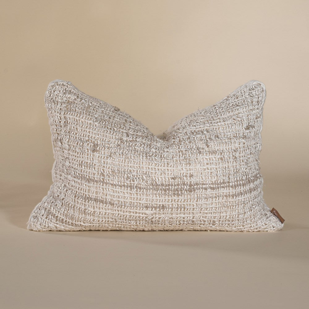 Handwoven textured cushion in a soft neutral hue, featuring intricate detailing and a relaxed, organic aesthetic, perfect for layering on a sofa or bed