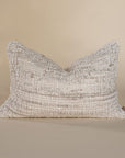 Handwoven textured cushion in a soft neutral hue, featuring intricate detailing and a relaxed, organic aesthetic, perfect for layering on a sofa or bed