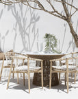 Spacious outdoor dining table with a woven rope base and white stone top, surrounded by natural wood chairs