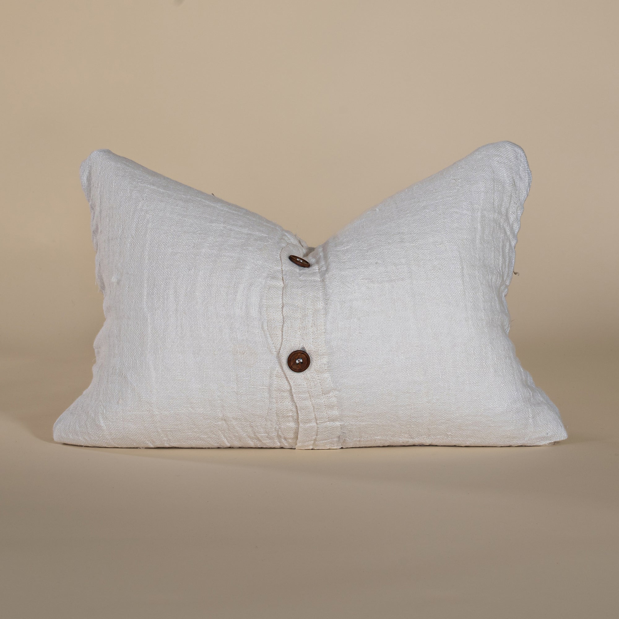 Soft linen lumbar cushion in a neutral tone, featuring a classic wooden button closure for a refined and timeless look