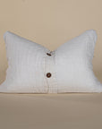 Soft linen lumbar cushion in a neutral tone, featuring a classic wooden button closure for a refined and timeless look