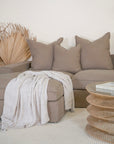 Linen slipcover sectional sofa styled in a modern living space. Showcasing plush neutral cushions, a textured throw, and a natural rattan coffee table for a relaxed, contemporary aesthetic.