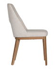 A contemporary dining chair from KULALA Living, featuring soft boucle upholstery and sturdy natural timber legs. Designed for comfort and style, perfect for modern dining spaces