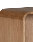 A modern oak bedside table from KULALA Living, featuring a curved silhouette and open storage shelf. Crafted from natural wood, this minimalist piece enhances any bedroom with its warm, organic aesthetic