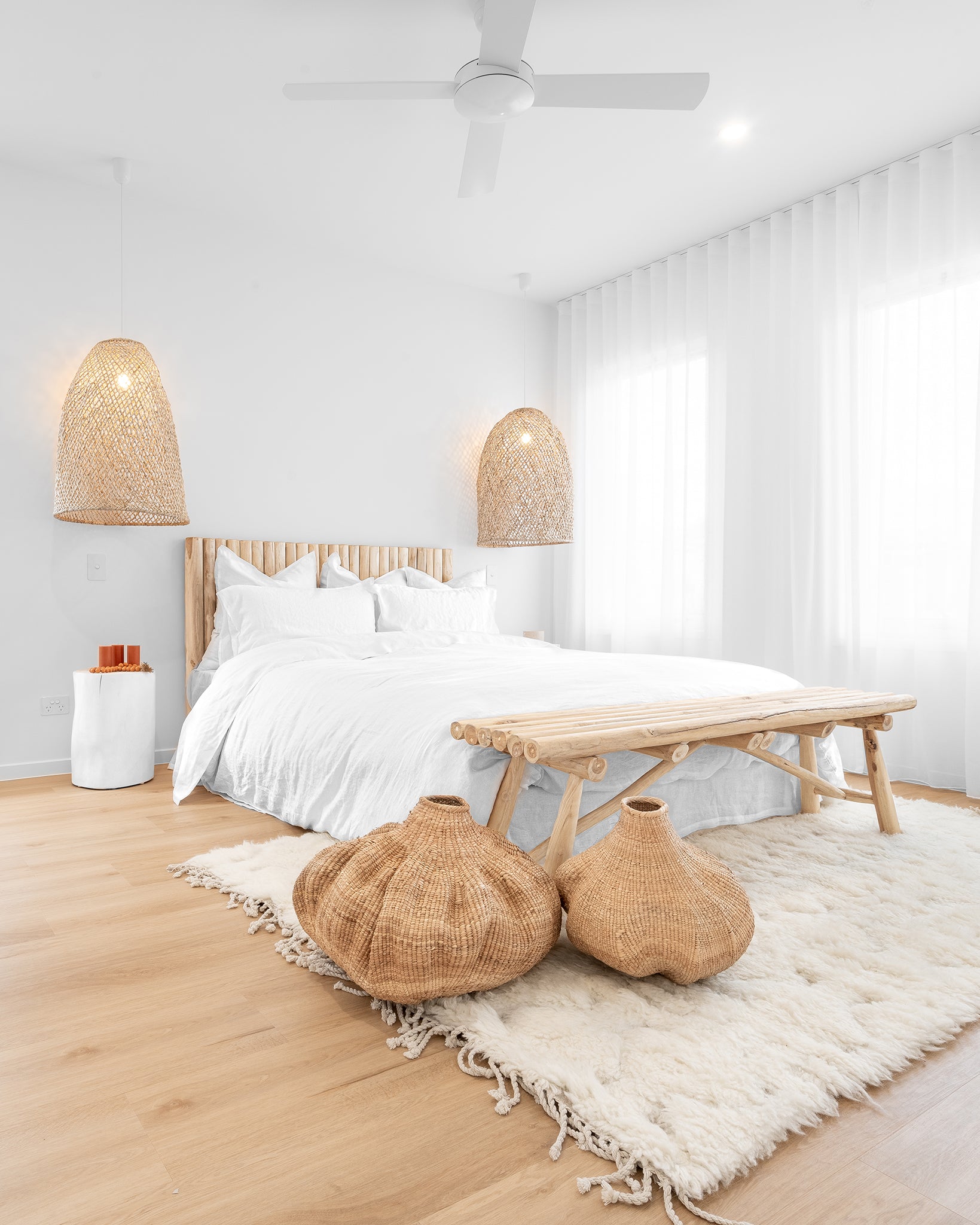 Serene bedroom featuring a timber bed frame, woven pendant lights, a wooden bench, and textured décor for a relaxed, organic aesthetic