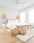 Serene bedroom featuring a timber bed frame, woven pendant lights, a wooden bench, and textured décor for a relaxed, organic aesthetic