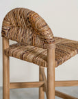 Handwoven rattan bar stool with a sturdy teak frame and curved backrest, showcasing organic texture and artisanal craftsmanship