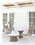 Outdoor lounge setting featuring woven rope chairs with white metal frames and matching side tables, styled with neutral cushions and ceramic decor under a pergola