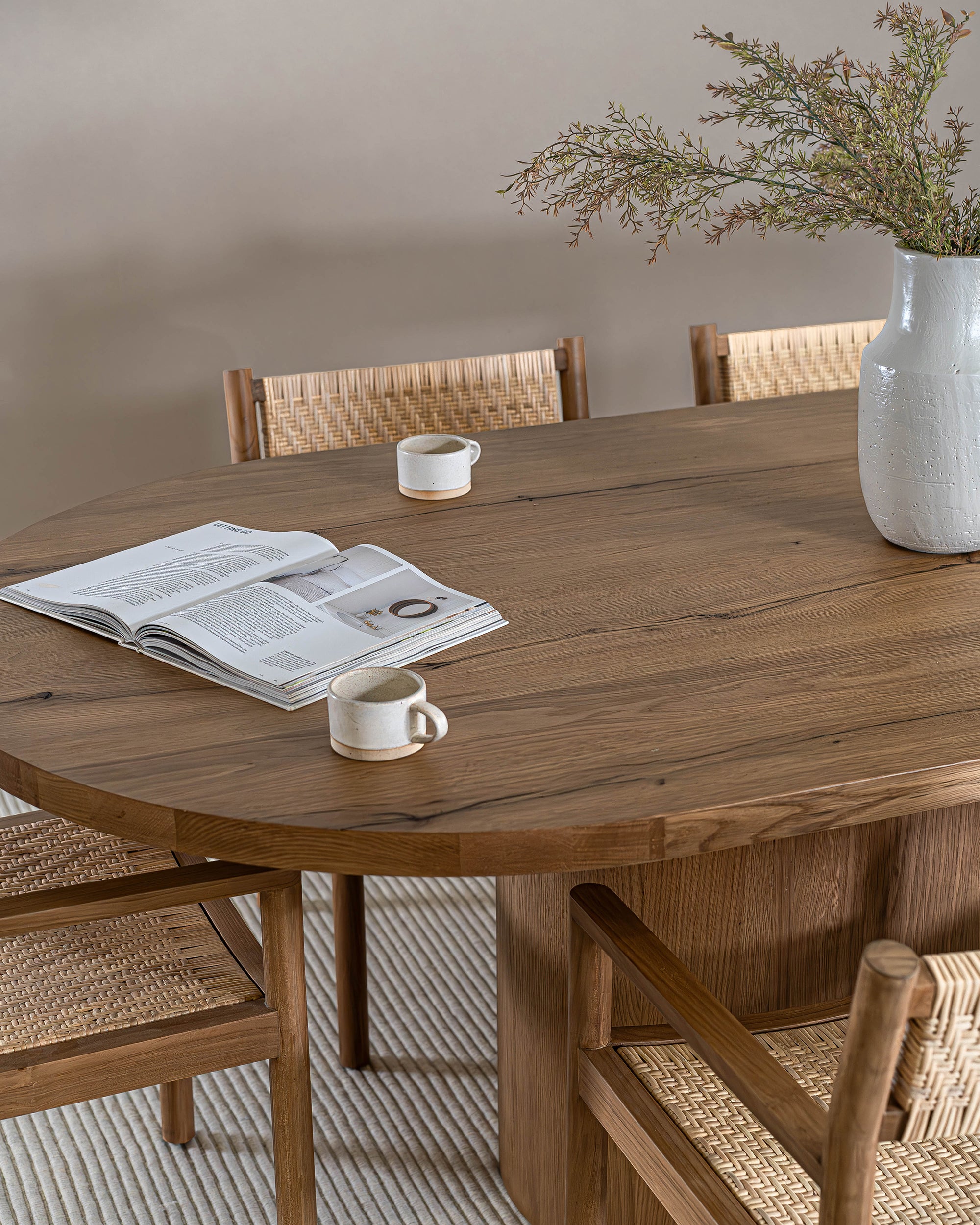 Elegant round oak dining table paired with woven rattan chairs, creating a warm and inviting dining space with natural textures