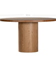 Contemporary round oak pedestal dining table featuring a sleek, minimalist design with a solid cylindrical base and smooth tabletop