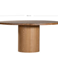 Contemporary round oak pedestal dining table featuring a sleek, minimalist design with a solid cylindrical base and smooth tabletop