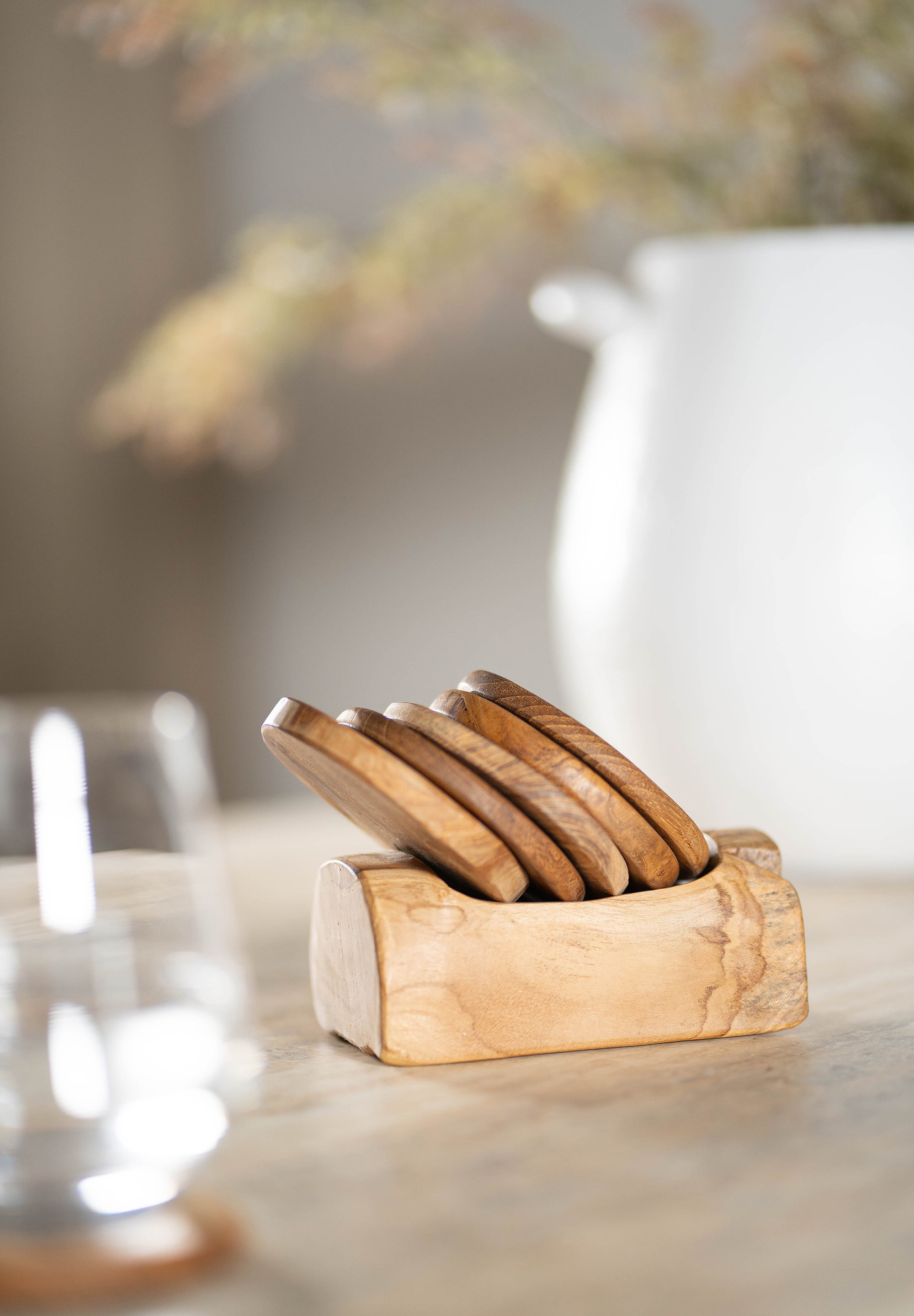 A beautifully crafted teak wood coaster set with a matching holder, adding warmth and natural texture to any dining or coffee table setting.