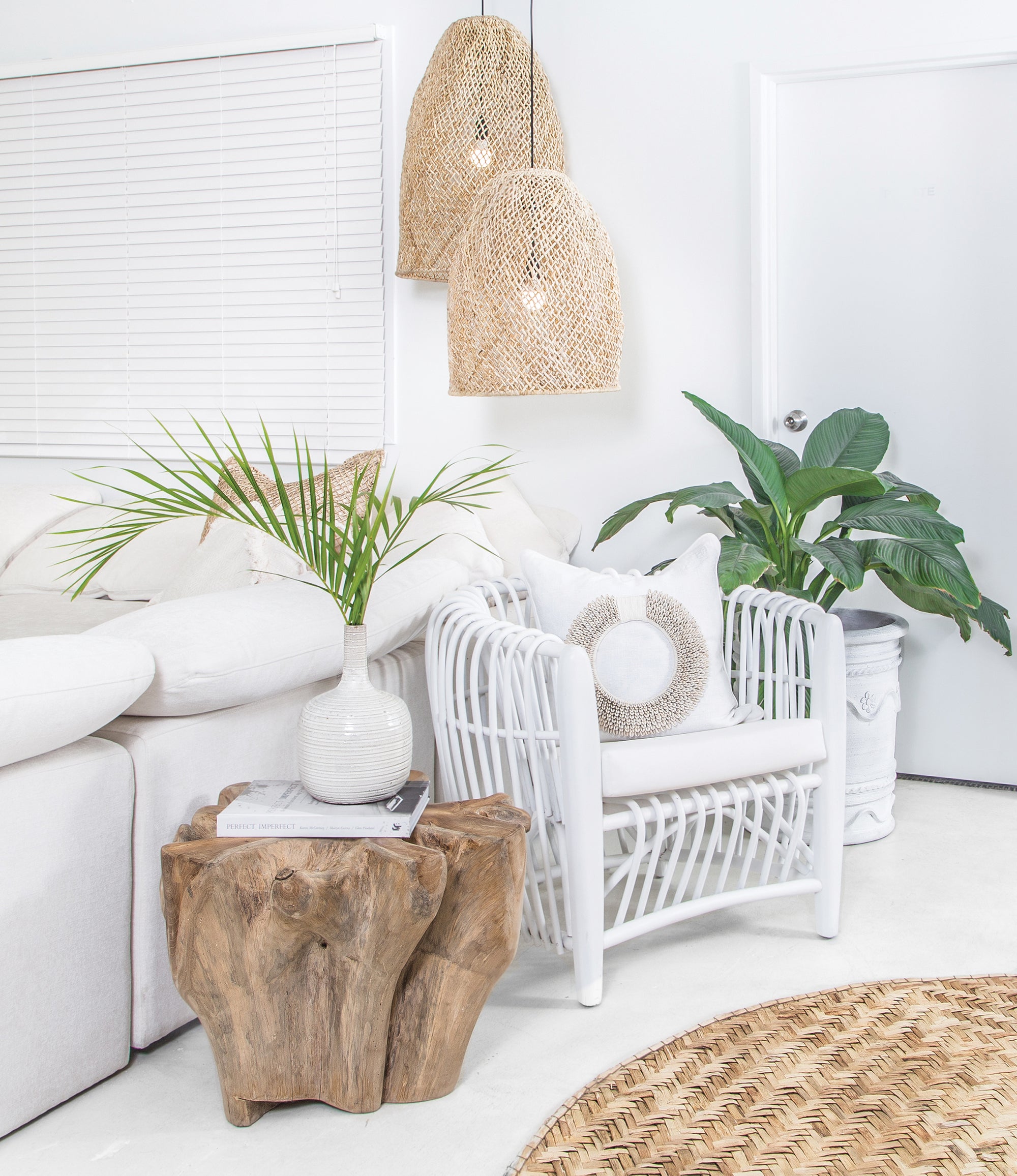 Coastal-inspired living space featuring a white rattan armchair, natural wood side table, and woven pendant lights, creating a serene and stylish interior