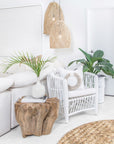 Coastal-inspired living space featuring a white rattan armchair, natural wood side table, and woven pendant lights, creating a serene and stylish interior