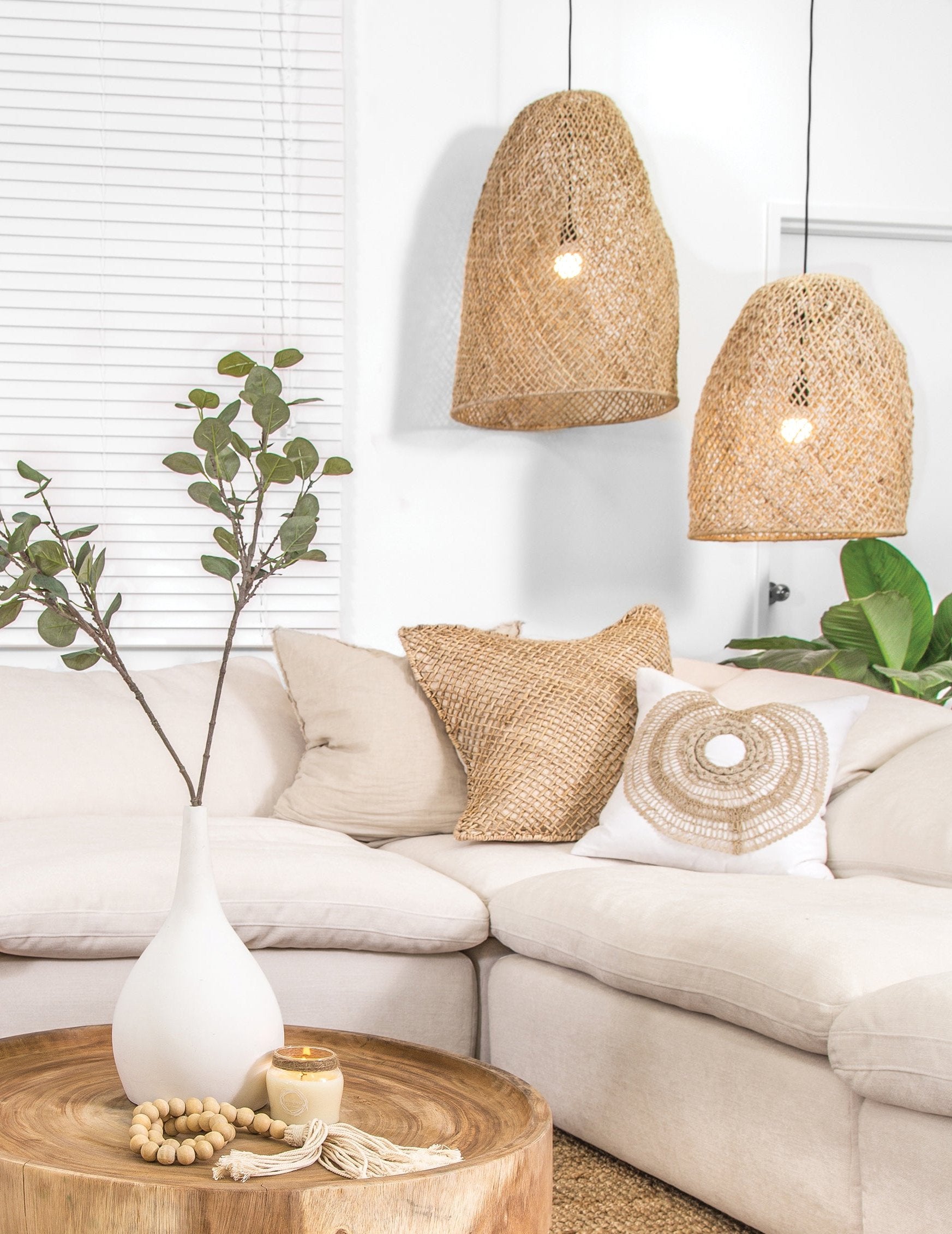 Relaxed living space featuring woven pendant lights, a natural linen sofa, and a wooden coffee table styled with organic décor elements