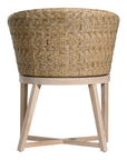 KULALA Living handwoven rattan dining chair with a curved backrest, natural wood legs, and a neutral seat cushion, blending coastal and contemporary design